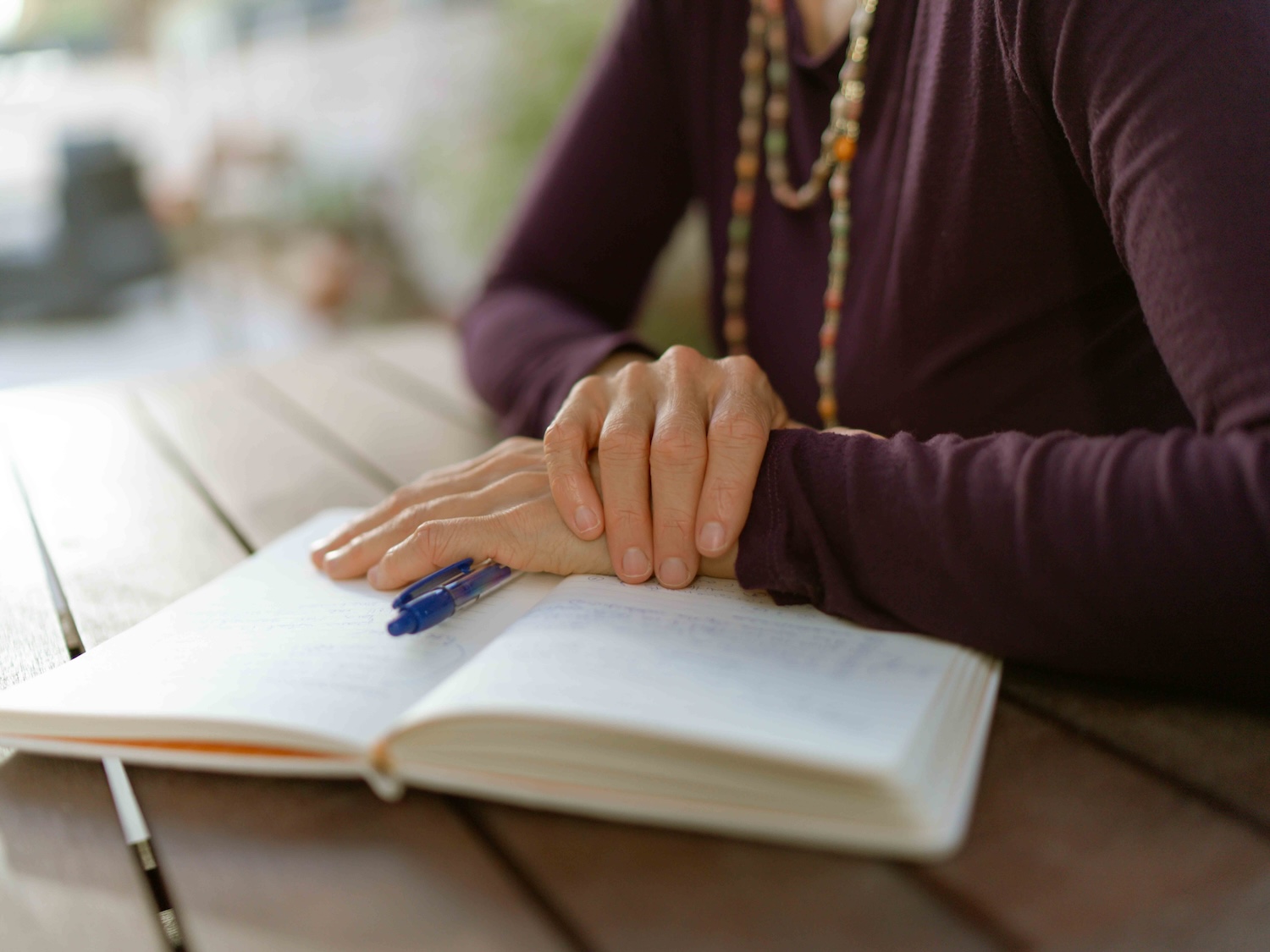 Hands resting on an open journal with a pen